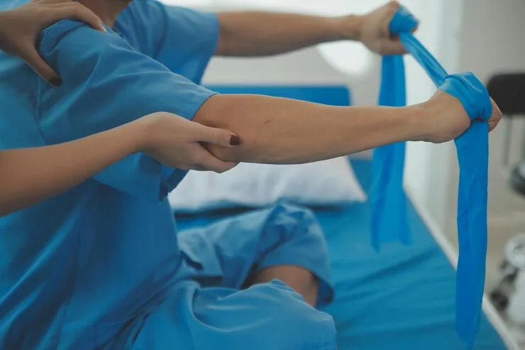close-up-hand-patient-doing-stretching-exercise-with-flexible-exercise-band-physical-therapist-hand-help-clinic-room_265022-94240