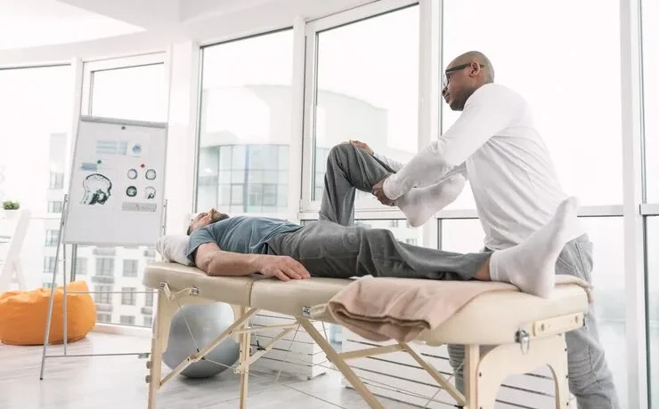 rehabilitation-program-professional-physical-therapist-holding-his-patients-leg-while-working-according-individual-rehabilitation-program_259150-2709