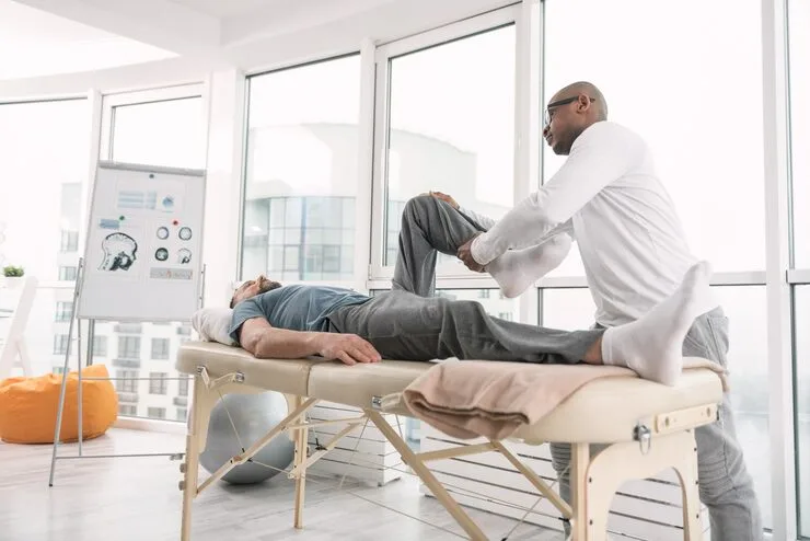 rehabilitation-program-professional-physical-therapist-holding-his-patients-leg-while-working-according-individual-rehabilitation-program_259150-2709